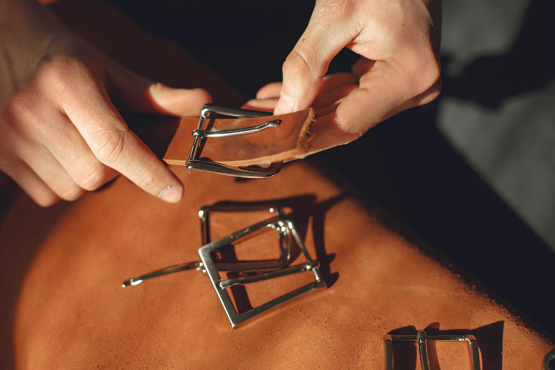 Crop man putting on metal clasp on leather strap