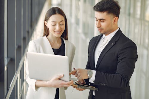 Focused diverse coworkers using laptop in office corridor