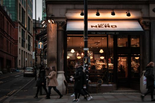 A lively street scene outside a coffee shop in Manchester, England.