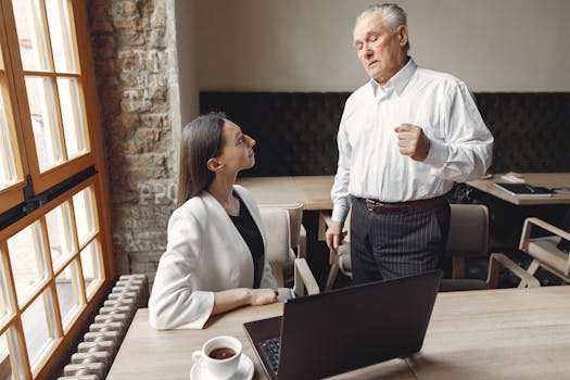 Two professionals engage in a serious discussion in a modern office with natural lighting and warm tones.