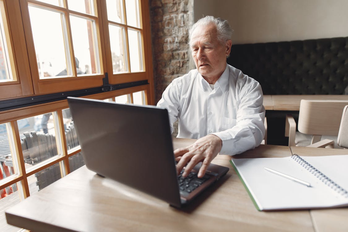 Free Elegant senior man using laptop in creative office Stock Photo