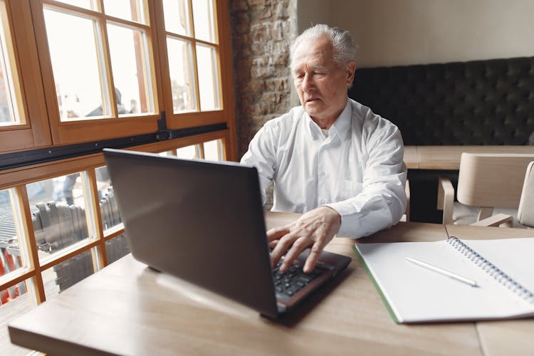 Elegant Senior Man Using Laptop In Creative Office