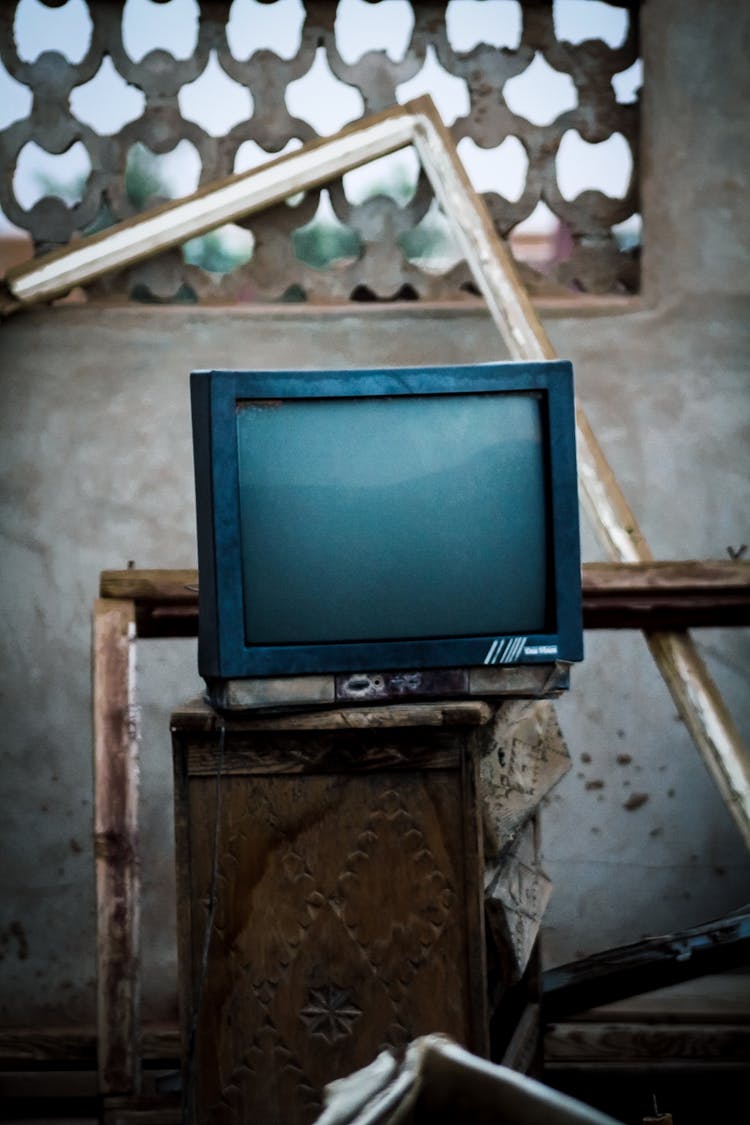 A Broken Television On A Wooden Shelf