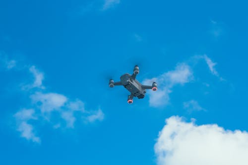 Free From below of bottom part of quadcopter with propellers and camera for taking photo and video in blue sky with clouds Stock Photo