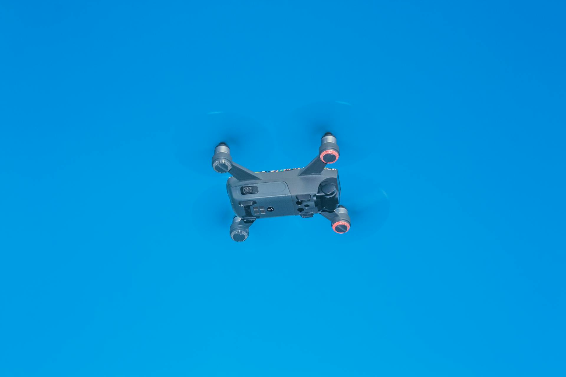 From below of side part of remote control drone with quickly spinning propellers and small cameras for taking photos and videos