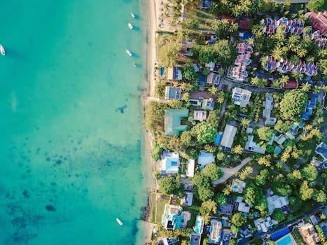 这是一幅壮丽的热带沿海村庄鸟瞰图，绿松石般的海水与郁郁葱葱的植被尽收眼底