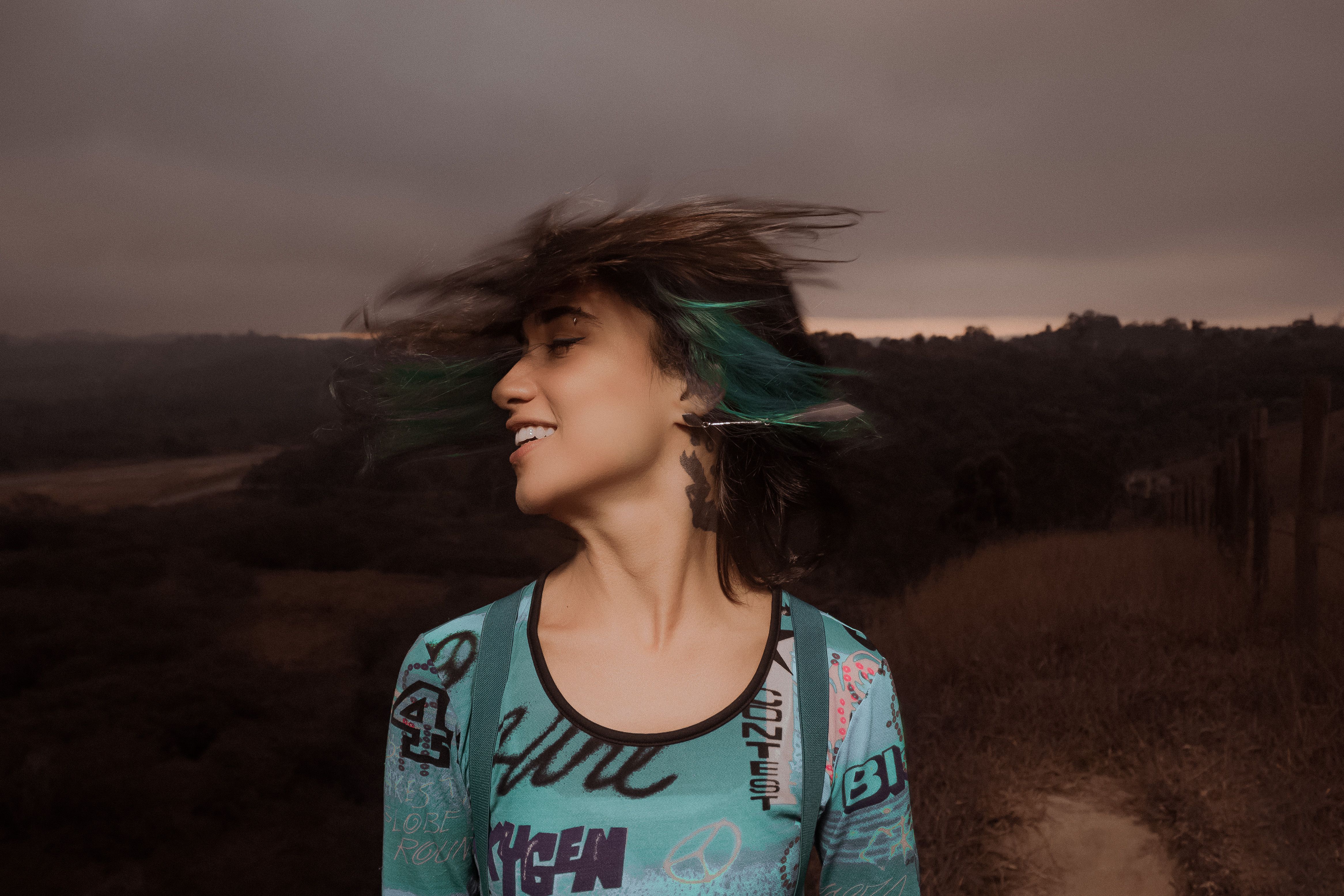 Cheerful young female with in casual wear with multi color hair spinning head with smile and eyes color in twilight