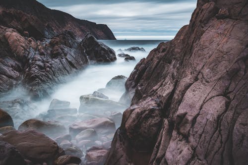 Dense fog above stones on coast of ocean