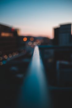 Defocused view of illuminated dark city with residential buildings under sunset blue clear sky