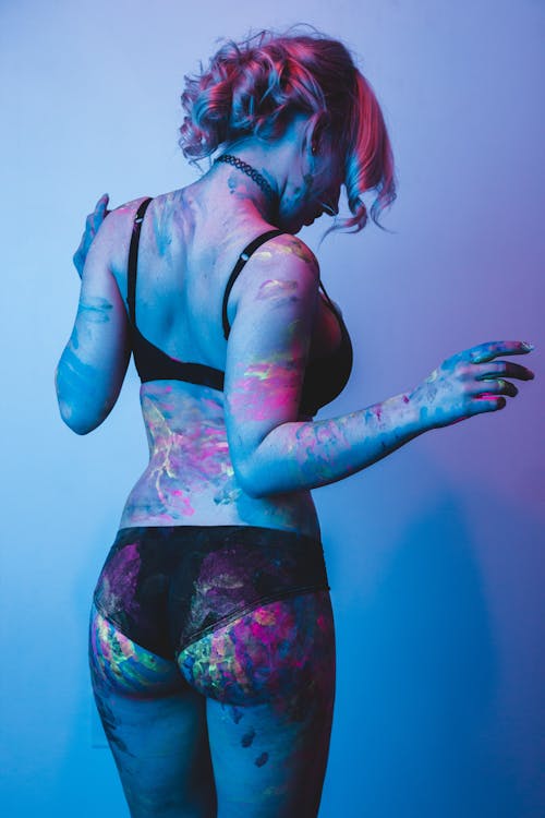 Sexy woman covered with paint glowing in ultraviolet
