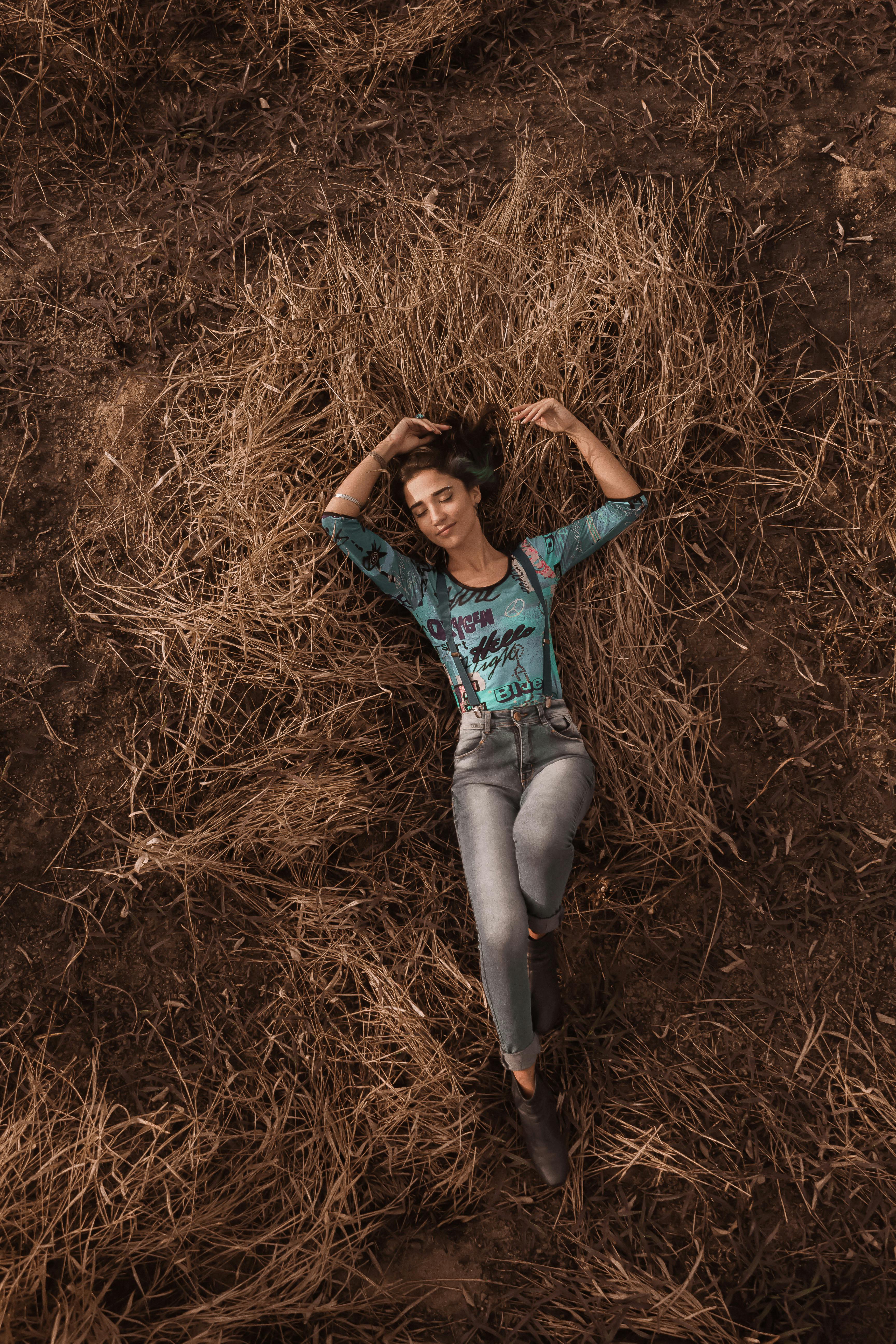 A serene moment of a woman lying on dried grass, embodying tranquility and nature.