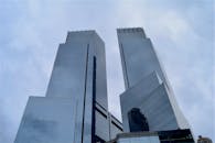 低角度镜头拍摄的现代摩天大楼，在多云天空下反射着玻璃外墙