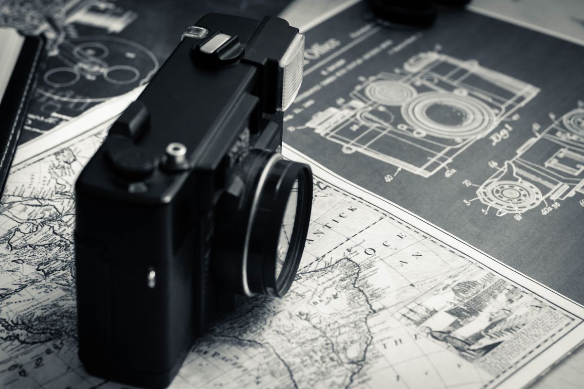 High angle of vintage photo camera placed on table with map and instructions for use