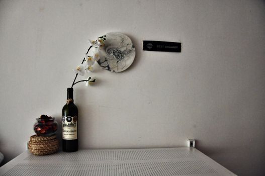 Composition with bottle with white flower placed near glass cup with dried petals