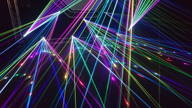 Faisceaux laser multicolores traversant la nuit lors d’un show laser