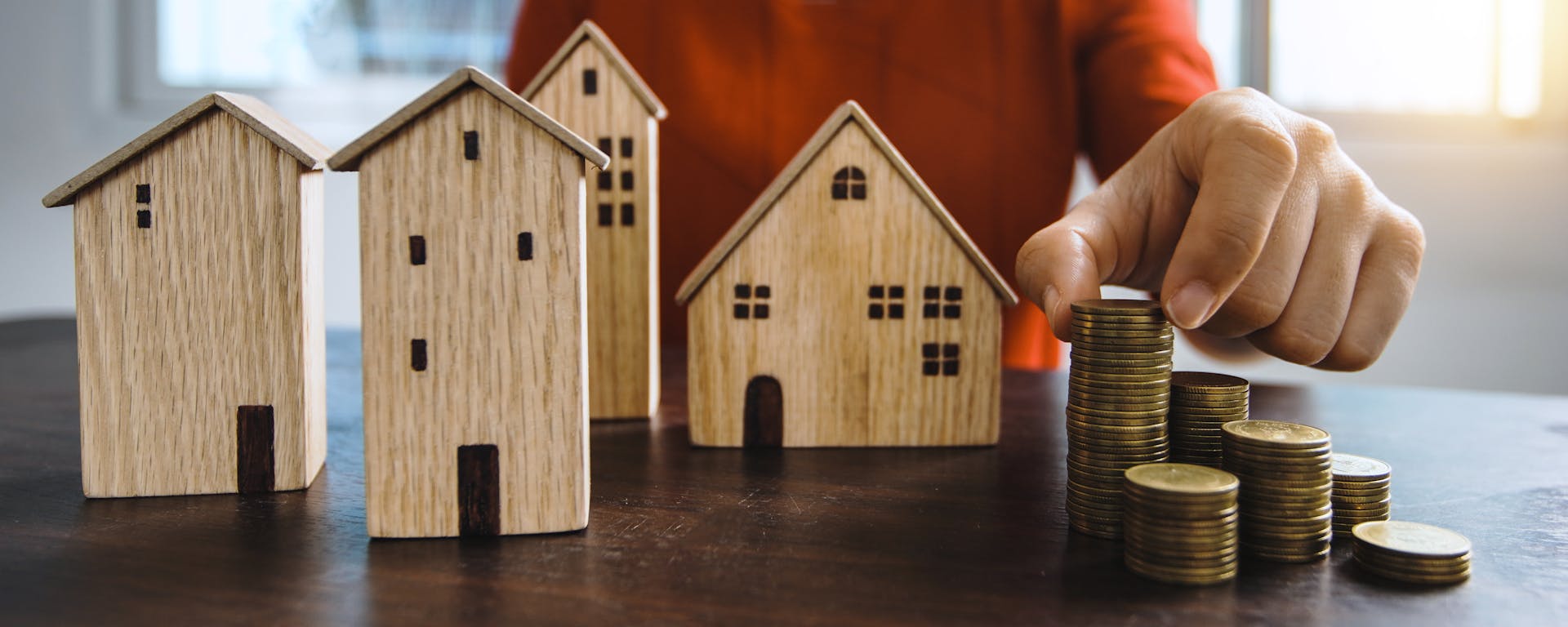 Planning investments with stacked coins and model houses on a table.