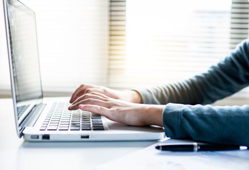 Close-up shot of hands typing on a laptop keyboard, perfect for business or technology themes.