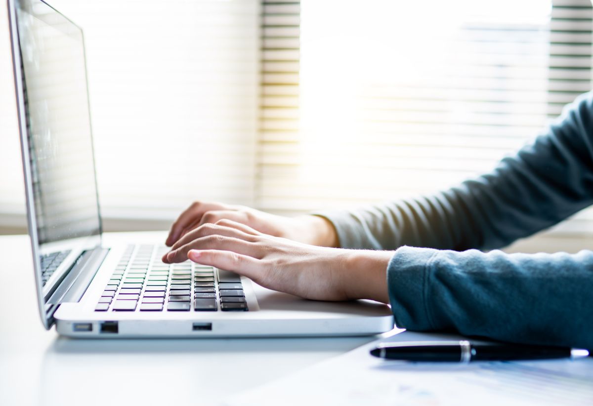 Person writing an email at a laptop