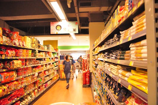 A woman wearing a mask shops in a grocery store, surrounded by various products on shelves.