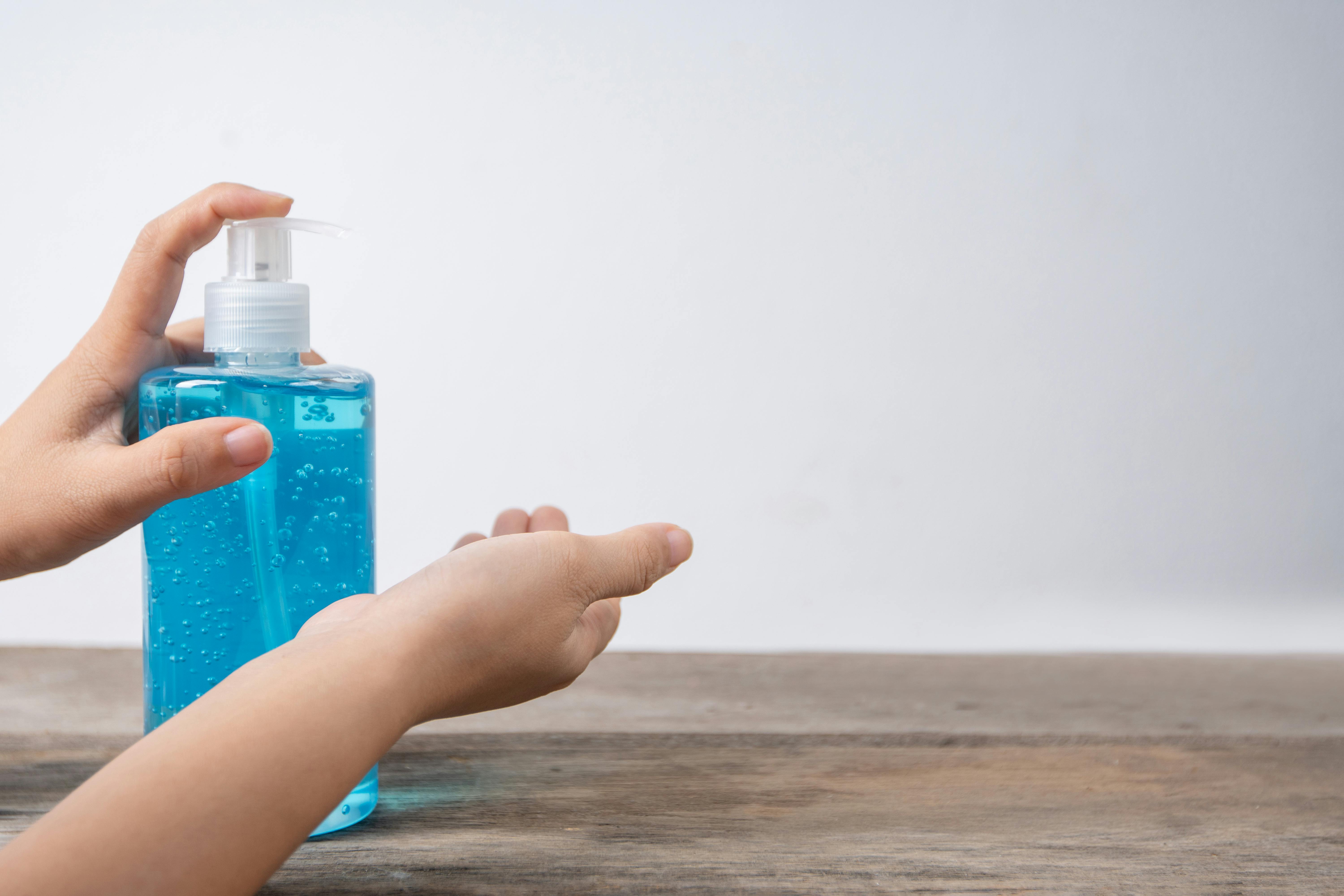 person using a hand sanitizer in plastic pump bottle
