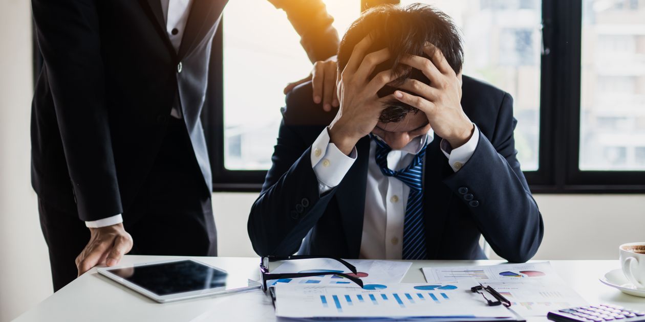 スーツ姿でストレスを感じる男性 — 完璧なプランを目指すことで追い詰められる初受験生のイメージ