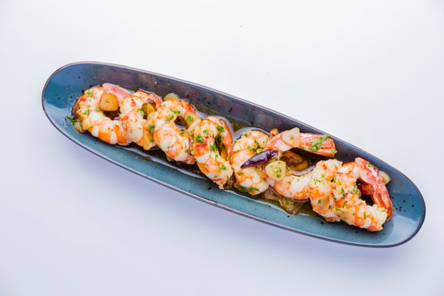 Close-up of a gourmet shrimp dish served on a stylish blue plate, perfect for seafood lovers.