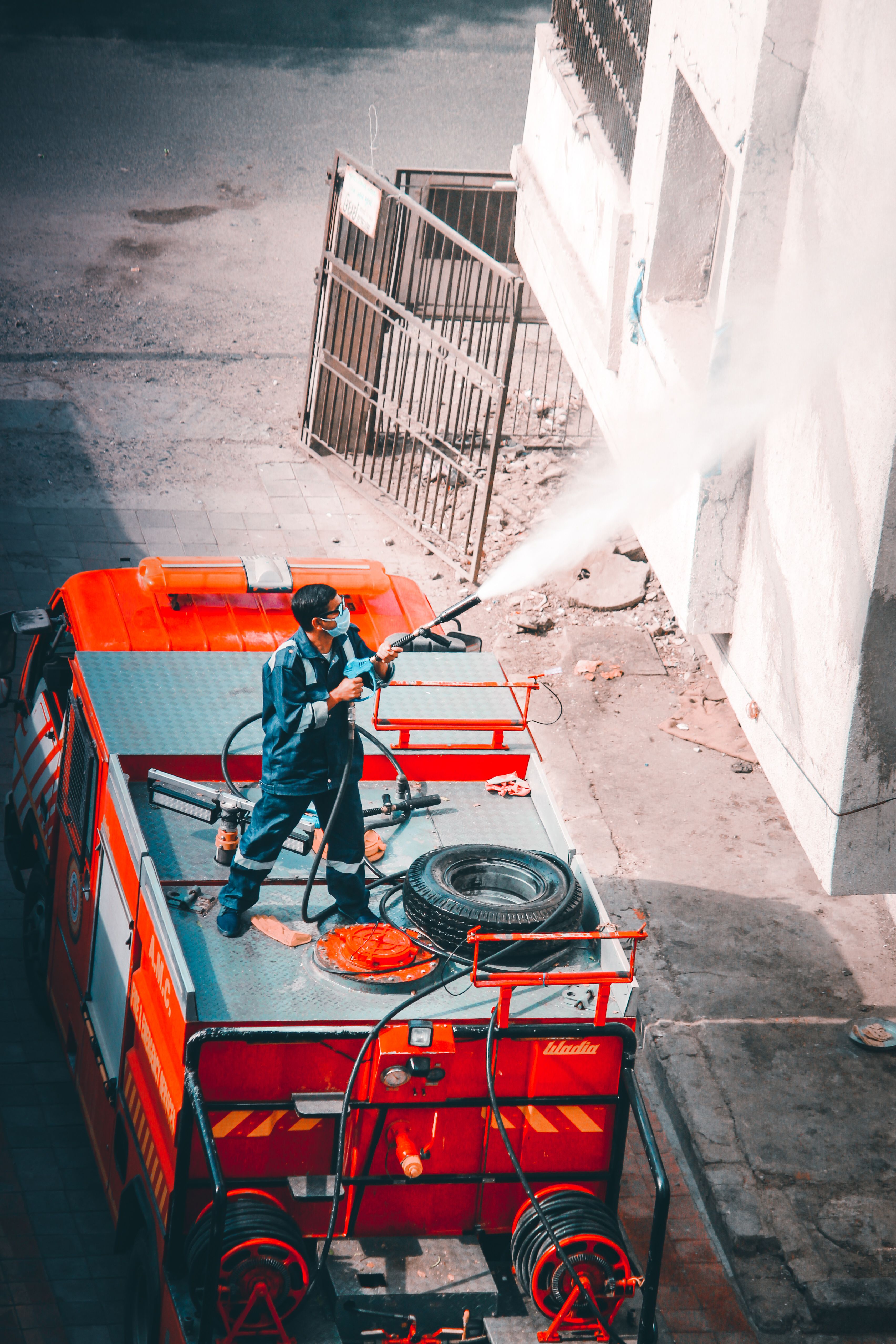 Man Standing On A Fire Truck Sanitizing A Building · Free Stock Photo