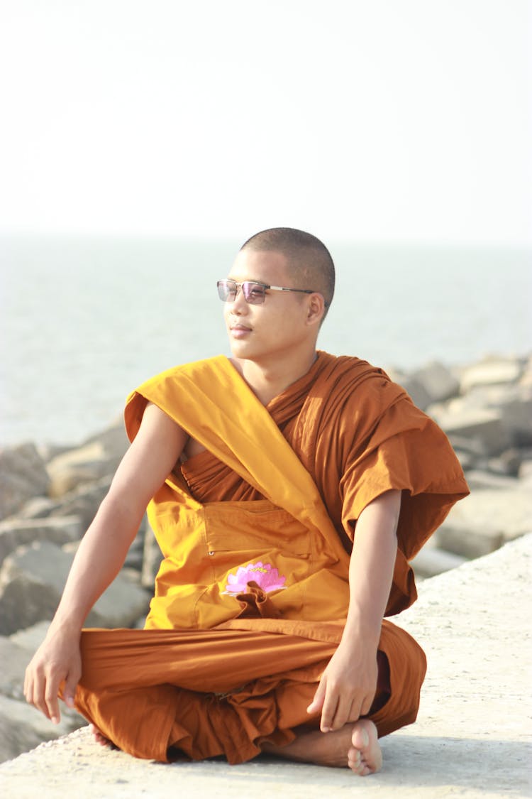 Man Wearing An Orange Robe Sitting On Concrete