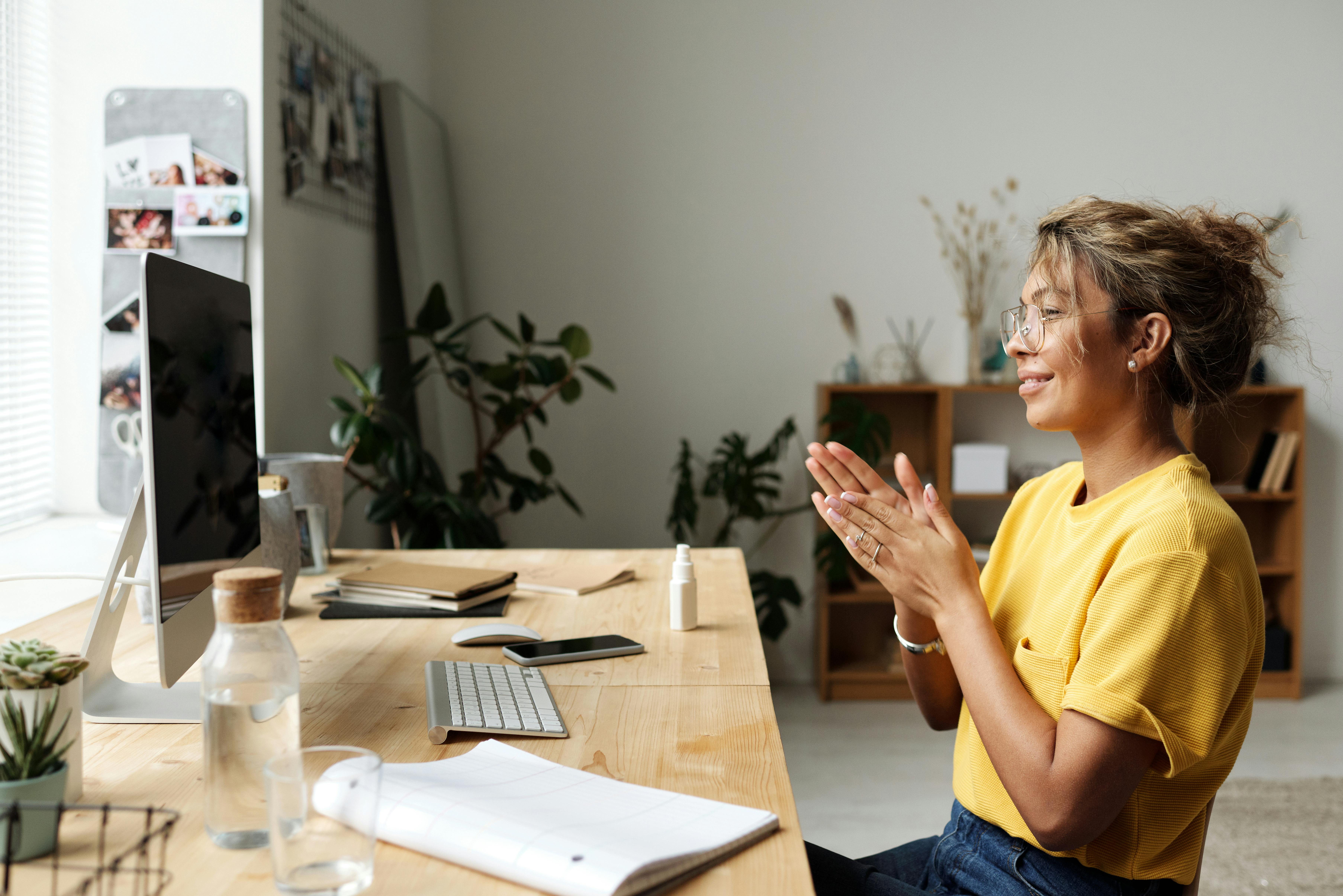 woman in yellow crew neck t shirt sitting on chair having a video chat