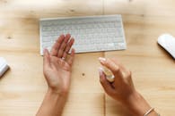 双手在木桌键盘旁使用消毒喷雾的特写