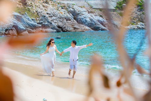 Unrecognizable couple walking on sandy beach near ocean during honeymoon