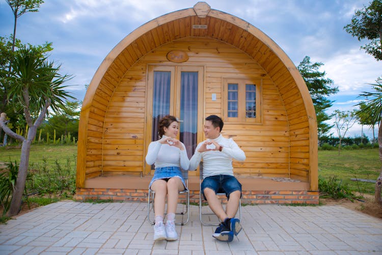 Asian Couple Showing Heart Gesture Near House In Countryside