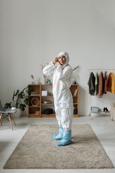 穿着全套防护服的女士在装饰现代的家居中调整引擎盖