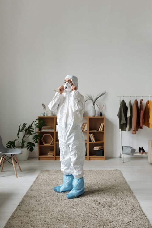 Free A person wearing protective gear adjusts their mask inside a stylish room. Stock Photo