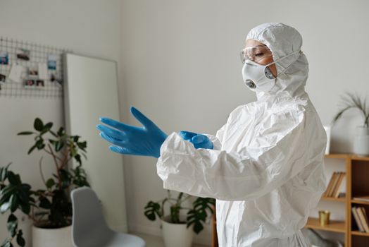 一名医护人员在室内穿着全套个人防护装备，包括口罩和手套