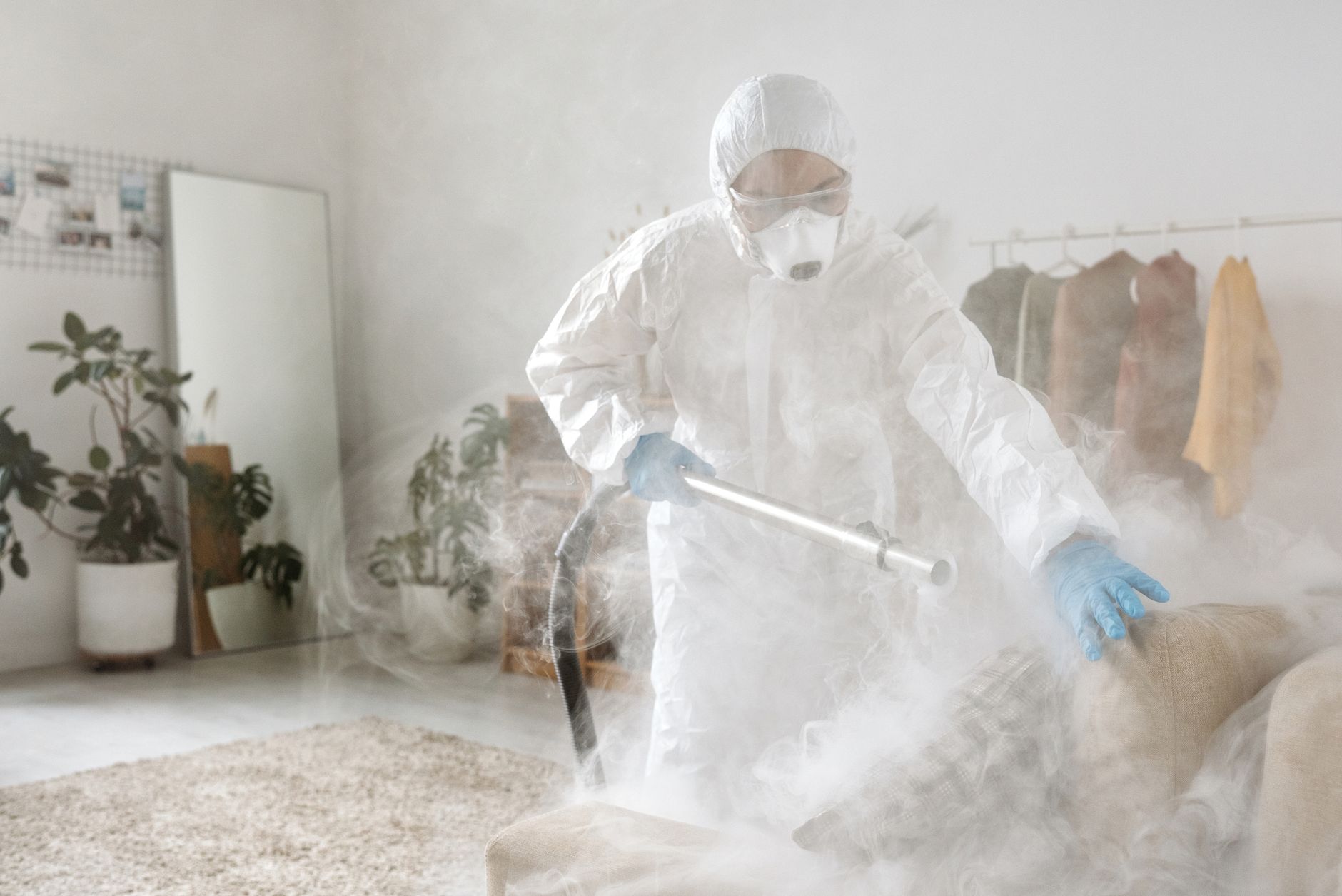 A person in protective suit disinfecting a room to eliminate viruses and bacteria.