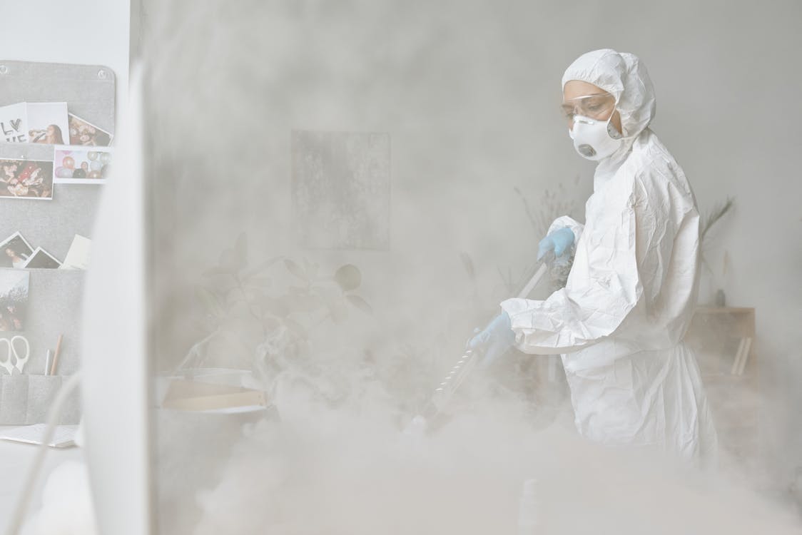 A Woman in Personal Protective Equipment Disinfecting 