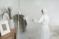 一名妇女身穿全套防护装备，使用熏蒸装置对室内空间进行消毒