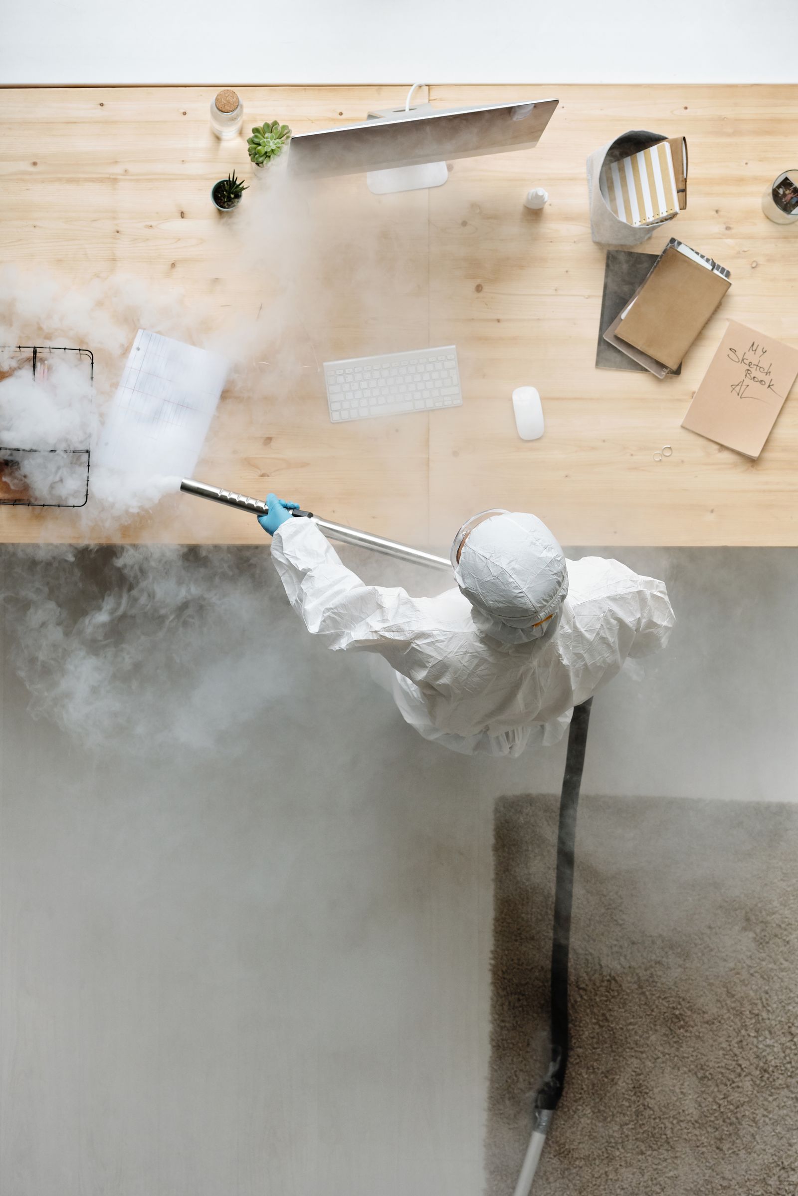 Sanitization technician disinfecting an office desk with steam