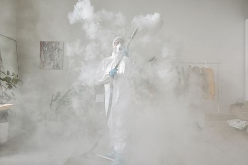 Free Person wearing PPE suit fogging a room for disinfection. Indoor safety measures. Stock Photo