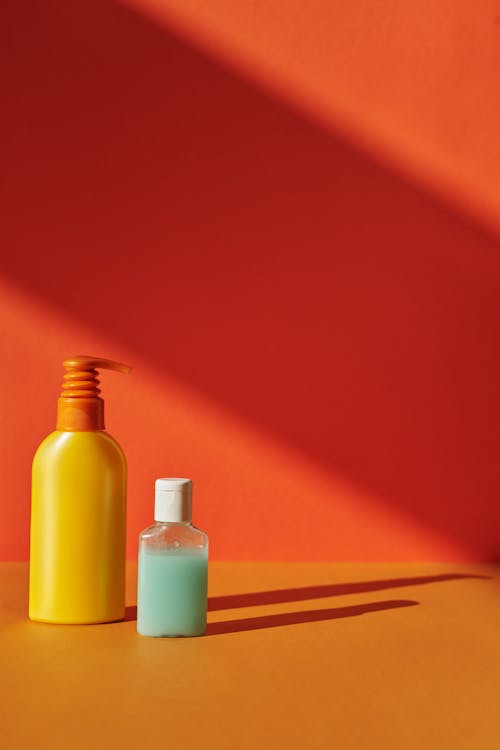 Free Yellow and Clear Plastic Bottle Containers on Orange Surface Stock Photo