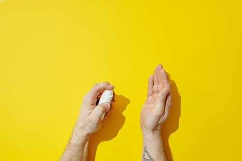 Hands of a Person Spraying White Plastic Bottle