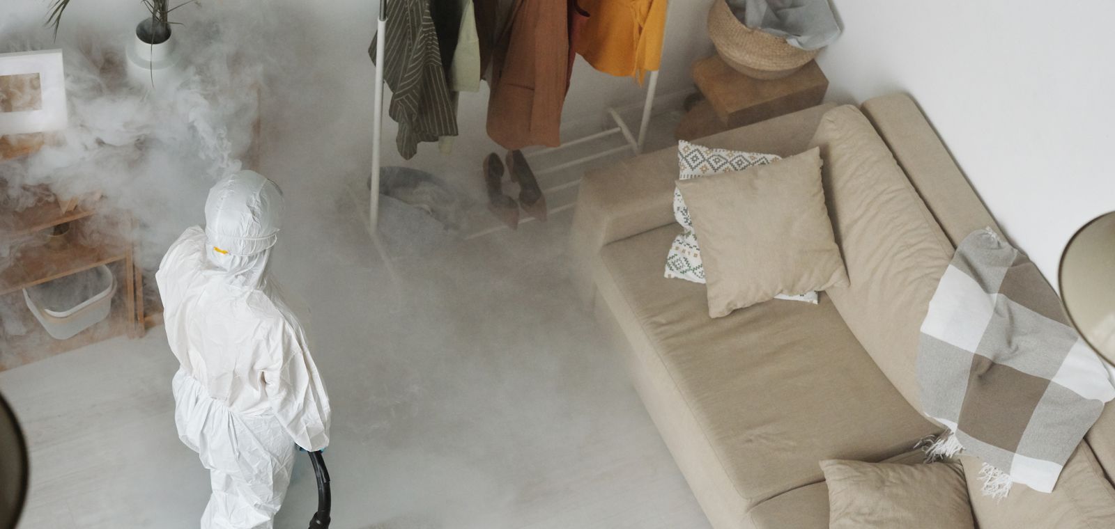 Technician in protective gear treating a living room
