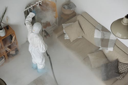 A Man Wearing White Protective Clothing Fumigating Clothes