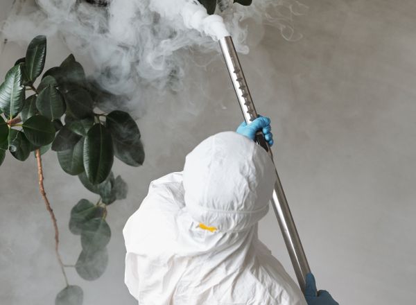 Worker in protective gear spraying indoors