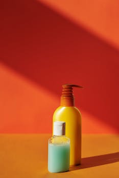 Vibrant liquid soap bottles against an orange background, perfect for hygiene or beauty concepts.
