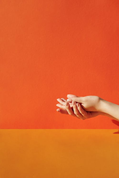 Person's Hands on Orange Wall