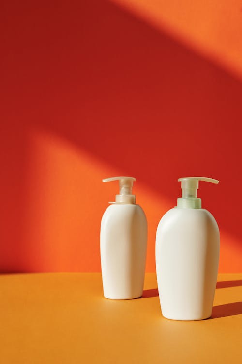 Two White Pump Bottles on Yellow Surface