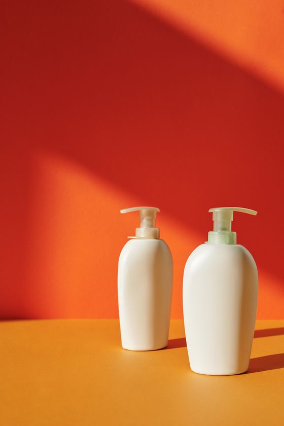 Two pump bottles against a bold orange backdrop. Photo by Edward Jenner on Pexels