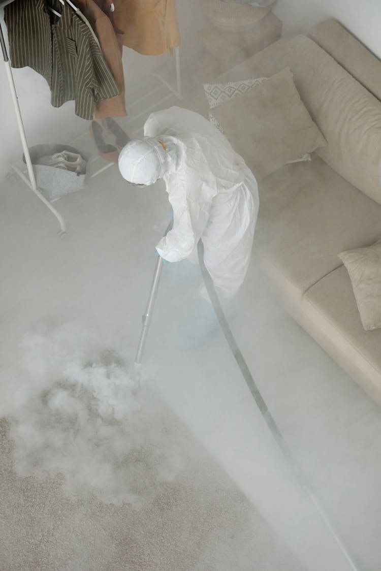 Person Wearing Protective Clothing Spraying Smoke On The Floor